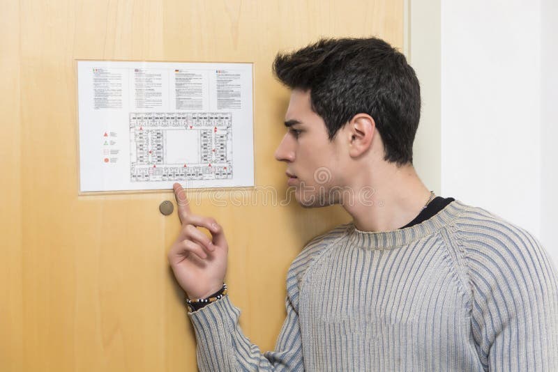 Ung man i hotell som pekar på floorplan arkivbild Ung man i hotell som pekar på floorplan arkivbild