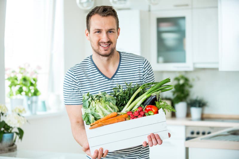 Young man with vegetable box in kitchen, family grocer shopping. Young man with vegetable box in kitchen, family grocer shopping