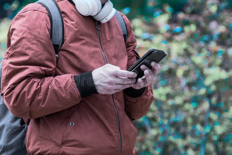 Ung man på den moderna gatan som väljer hörlursmusik på smartphone royaltyfri fotografi