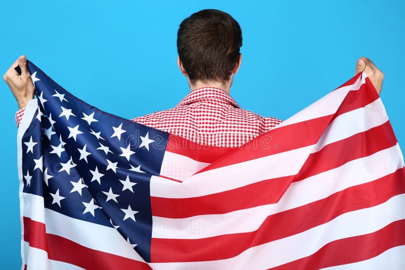 Ung man som rymmer en amerikanska flaggan royaltyfria bilder Ung man som rymmer en amerikanska flaggan royaltyfria bilder