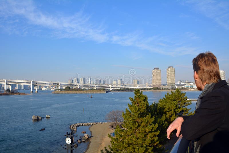 Ung man som ser regnbågebron i den Tokyo staden japan fotografering för bildbyråer Ung man som ser regnbågebron i den Tokyo staden japan fotografering för bildbyråer