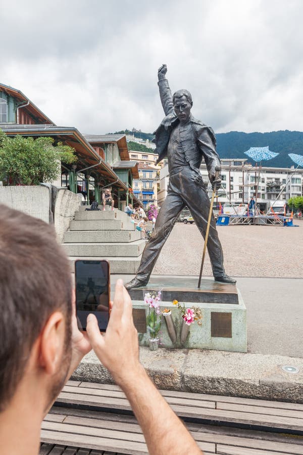 Ung man som tar fotoet av den berömda Freddie Mercury statyn på marknadsfyrkanten som vänder mot sjöGenèvegummilacka Leman i Mont royaltyfria foton Ung man som tar fotoet av den berömda Freddie Mercury statyn på marknadsfyrkanten som vänder mot sjöGenèvegummilacka Leman i Mont royaltyfria foton
