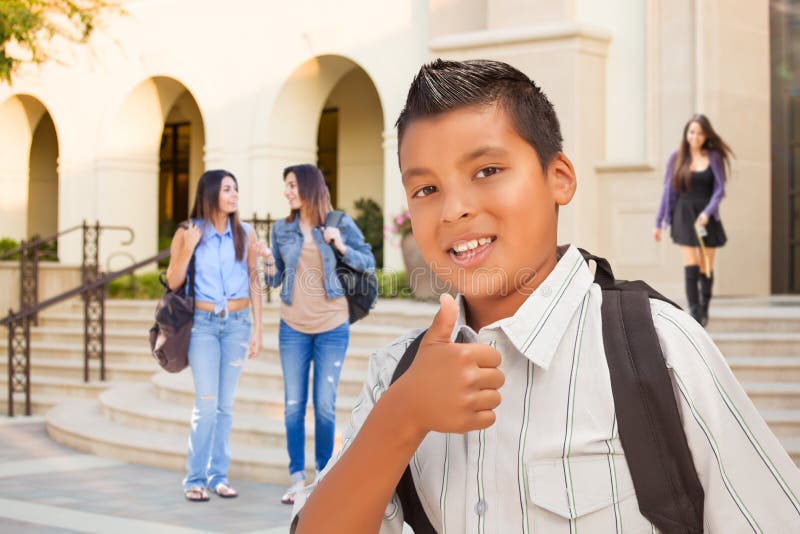 Ung manlig latinamerikansk student Boy Gives Thumbs upp på universitetsområde royaltyfri foto Ung manlig latinamerikansk student Boy Gives Thumbs upp på universitetsområde royaltyfri foto