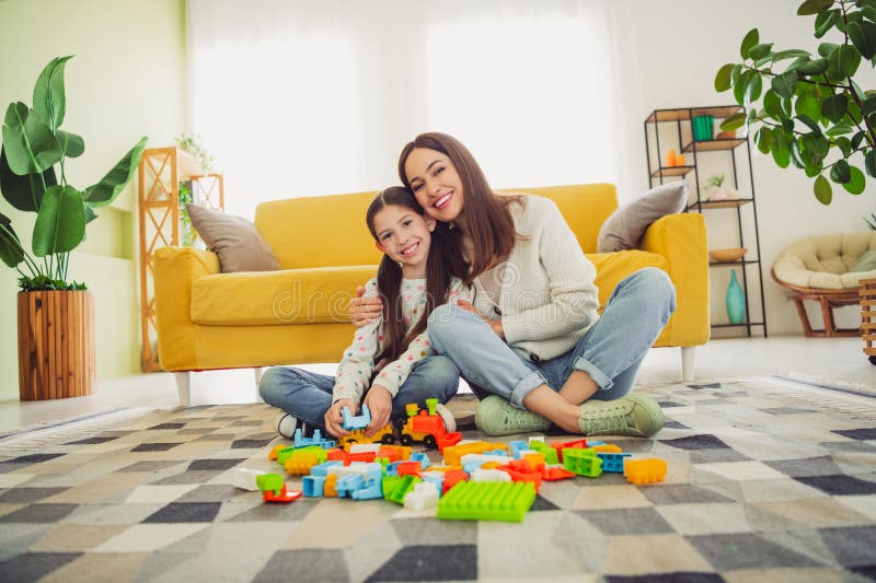 Ung mor och dotter njuter av lekande stunder med färgstarka block i ett ljust vardagsrum royaltyfria foton