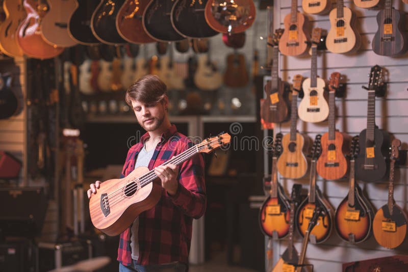 Ung musiker med en gitarr i ett lager arkivbild