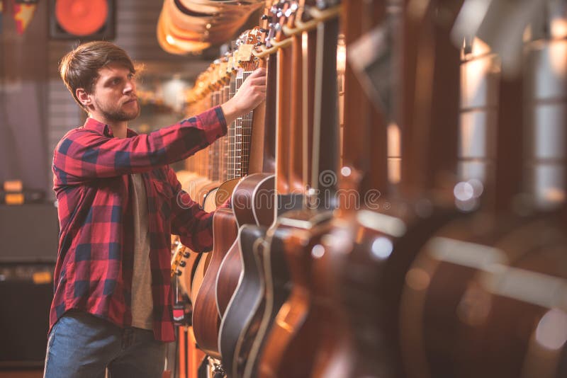 Ung musiker med en gitarr inomhus arkivfoton