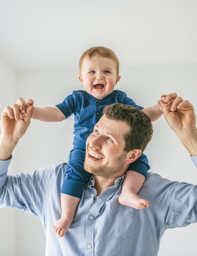 Ung pappa med en babypojke som hade kul med sin son nära ett fönster arkivbild