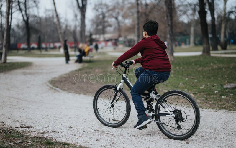 Ung pojke som cyklar i en stadspark på en lätt helg med naturglädje arkivfoton