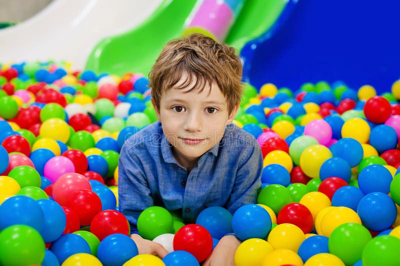 Ung pojke som har gyckel som spelar med färgrika plast- bollar royaltyfri bild Ung pojke som har gyckel som spelar med färgrika plast- bollar royaltyfri bild