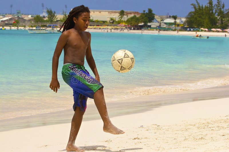 Ung pojke som spelar fotboll på stranden i Barbados som är karibiska royaltyfria foton Ung pojke som spelar fotboll på stranden i Barbados som är karibiska royaltyfria foton