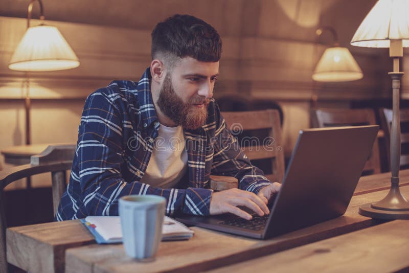 Ung professionell som surfar internet på hans bärbar dator i ett kafé royaltyfri foto Ung professionell som surfar internet på hans bärbar dator i ett kafé royaltyfri foto