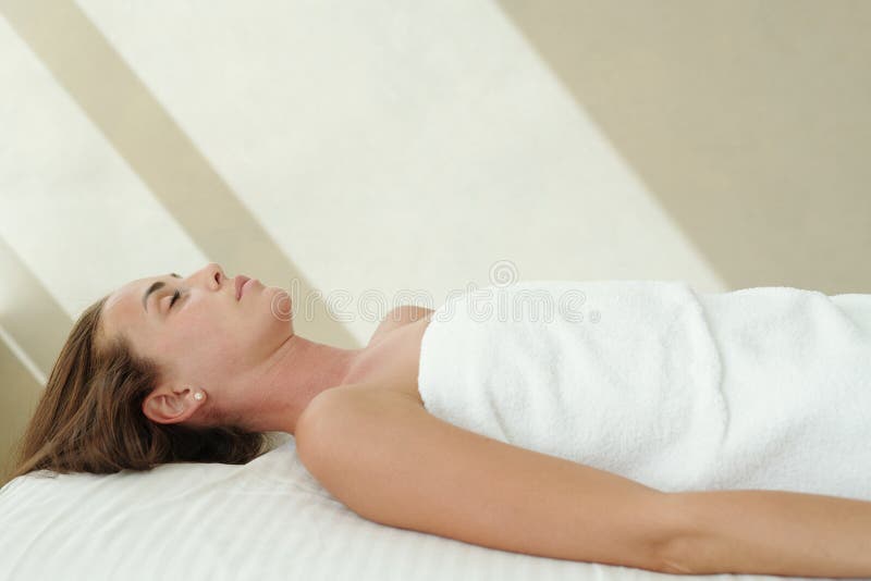 Ung relaxad kvinna som ligger på massagebord royaltyfria bilder