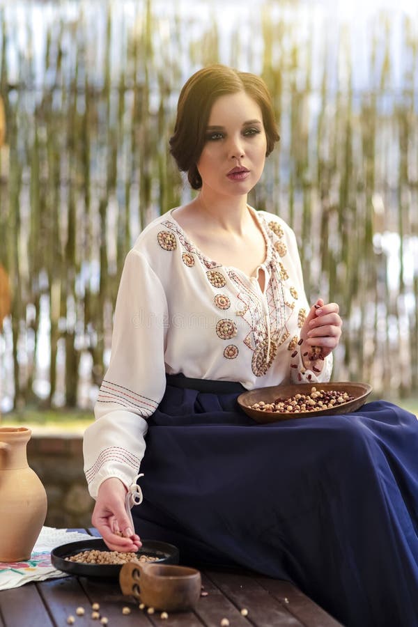 Ung sensuell hemmafru i byklänning som plockar färgstarka njurbönor på bordet i landskapsmiljön royaltyfri foto