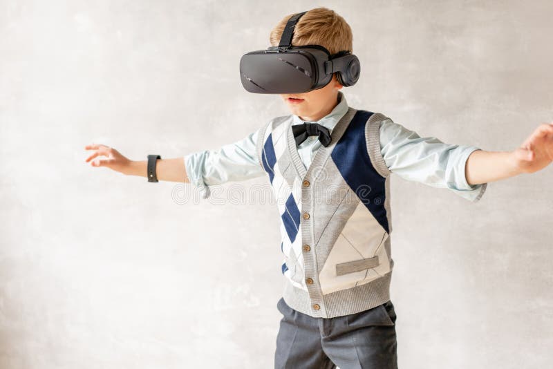 Ung skolpojke i VR-hörlurar med mikrofon att undersöka utrymme runt om honom royaltyfri bild Ung skolpojke i VR-hörlurar med mikrofon att undersöka utrymme runt om honom royaltyfri bild
