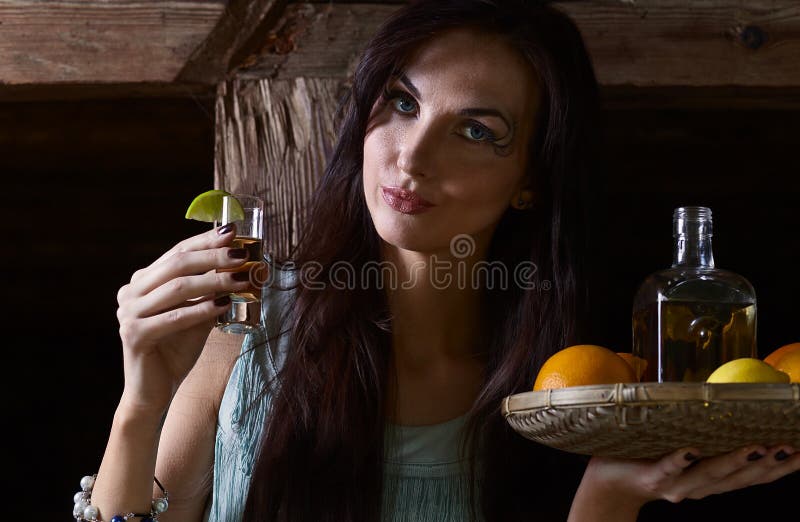 Ung skönhet med tequila i det gamla trähuset arkivbild Ung skönhet med tequila i det gamla trähuset arkivbild