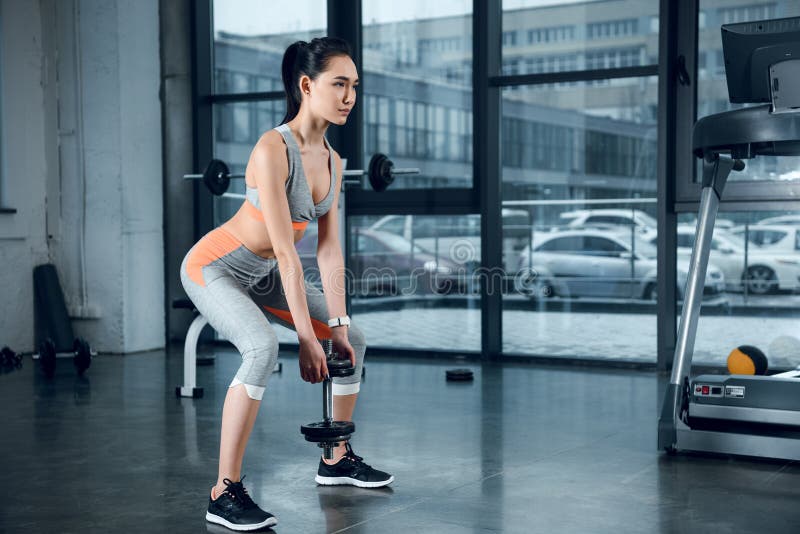 ung sportig kvinna som gör squats med viktplattor