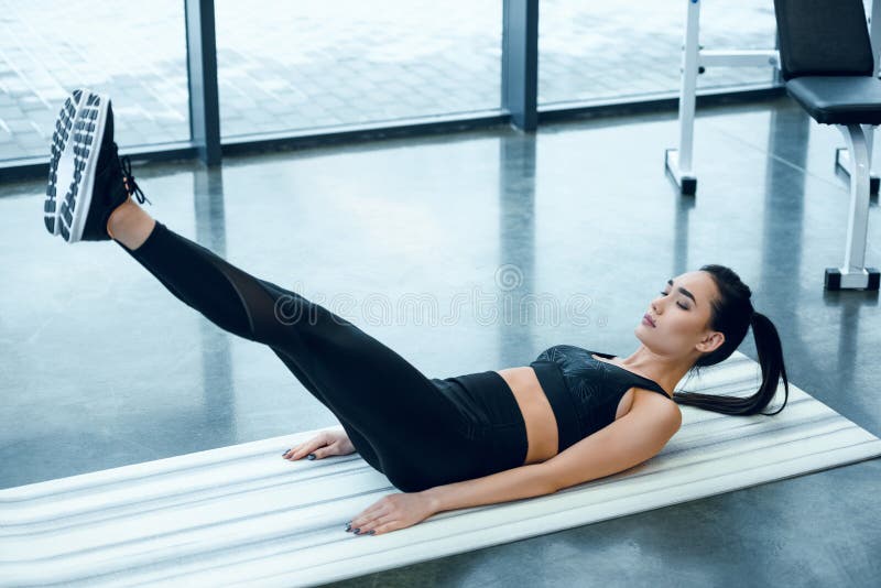 ung sportig kvinna som gör V-UPS på matt yoga