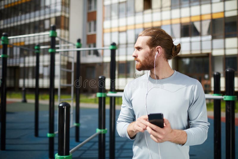 Ung sportig man som lyssnar till musik på sportjordning arkivfoto Ung sportig man som lyssnar till musik på sportjordning arkivfoto