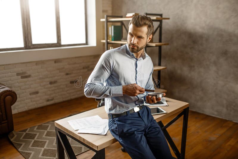 Ung stilig affärsmanhållcigarr och att posera i hans eget kontor Han ser för att sid och sitta på tabellen Säker sexig alfabetisk arkivbilder Ung stilig affärsmanhållcigarr och att posera i hans eget kontor Han ser för att sid och sitta på tabellen Säker sexig alfabetisk arkivbilder