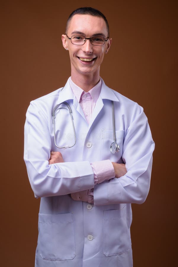 Ung stilig androgyn mandoktor mot brun bakgrund royaltyfria foton Ung stilig androgyn mandoktor mot brun bakgrund royaltyfria foton