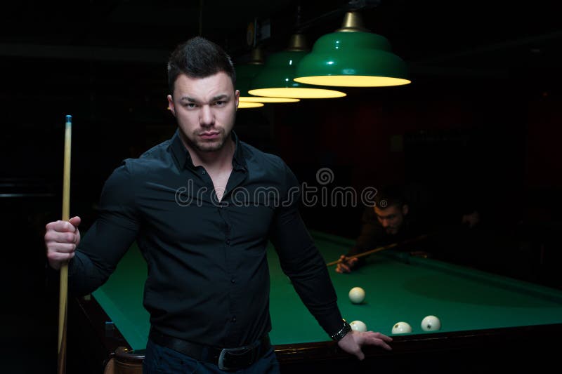 Ung stilig man med stickrepliken som spelar billiard arkivfoton Ung stilig man med stickrepliken som spelar billiard arkivfoton