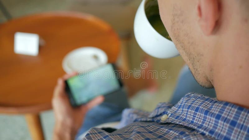 Ung stilig man som dricker Matcha grönt te och håller ögonen på videoen på mobiltelefonen i kafét Slowmotion livsstil för HD lager videofilmer