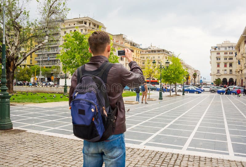 Ung turist med ryggsäcken som tar bilder av fyrkantiga en Archeas marknadsplatser och en fot- gata på en smartphone i Thessalonik royaltyfri bild Ung turist med ryggsäcken som tar bilder av fyrkantiga en Archeas marknadsplatser och en fot- gata på en smartphone i Thessalonik royaltyfri bild