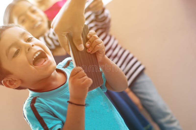 Young Kid screaming while parent trying to take away Mobile Phone with kids laughing from behind at home. Young Kid screaming while parent trying to take away Mobile Phone with kids laughing from behind at home.