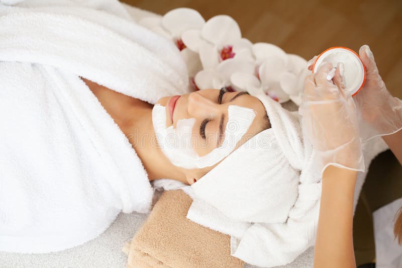 Ung vacker flicka som får ansiktsmask i spa skönhetssalon royaltyfri fotografi