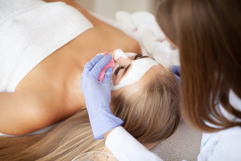 Ung vacker flicka som får ansiktsmask i spa skönhetssalon fotografering för bildbyråer