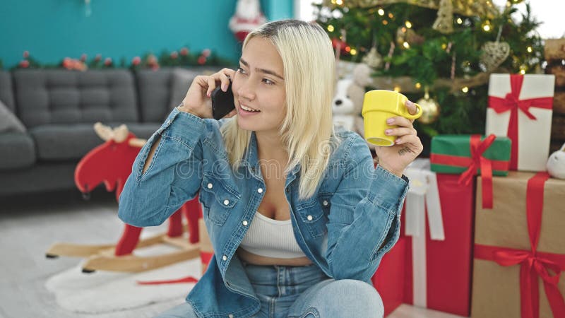 Ung, vacker historisk kvinna som pratar på smartphone och dricker kaffe och firar jultoma hemma royaltyfri bild
