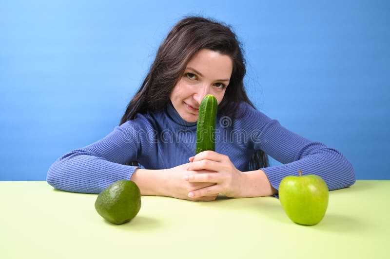 Ung vacker kvinna som håller gurka i händerna. vegetariankoncept arkivfoto