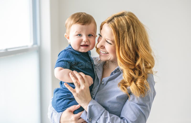 Ung, vacker mor med en babypojke i studio arkivfoton