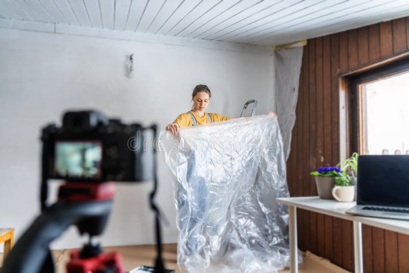 Ung vuxen kvinna som filmar en logg om att renovera ett hus royaltyfri fotografi