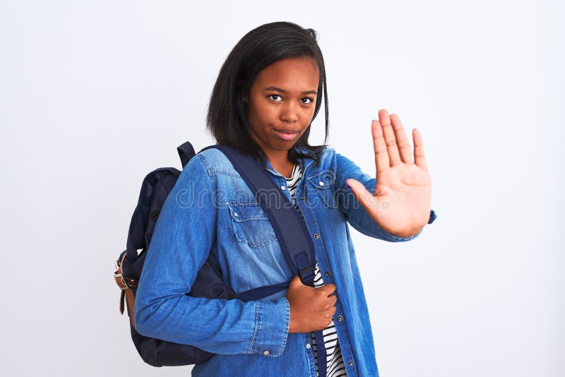 Unga afrikanska studentkvinnor som bär ryggsäck över isolerad bakgrund med öppen hand och gör stoppskylt med allvarliga och arkivbild