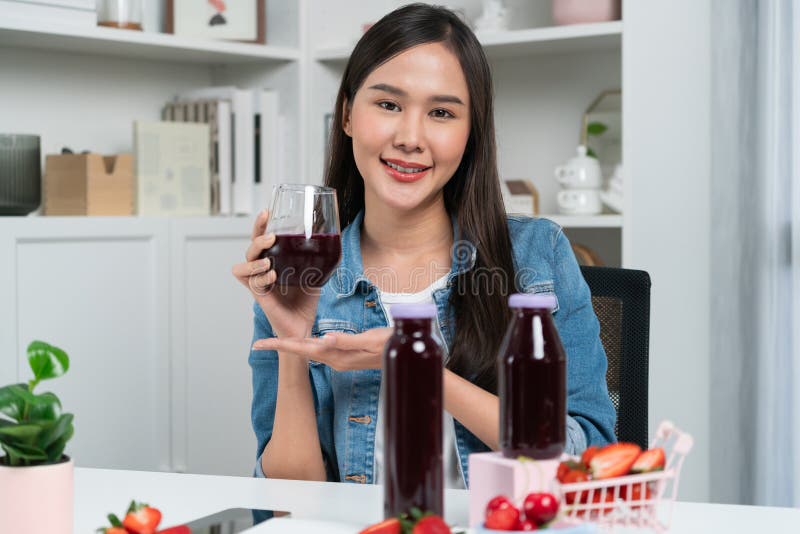 Smiling young beautiful Asian reviewing tasty mixed strawberry and cherry juice detox drinks, showing healthy product to promote for special promotion selling on social media online record. Stratagem. Smiling young beautiful Asian reviewing tasty mixed strawberry and cherry juice detox drinks, showing healthy product to promote for special promotion selling on social media online record. Stratagem.