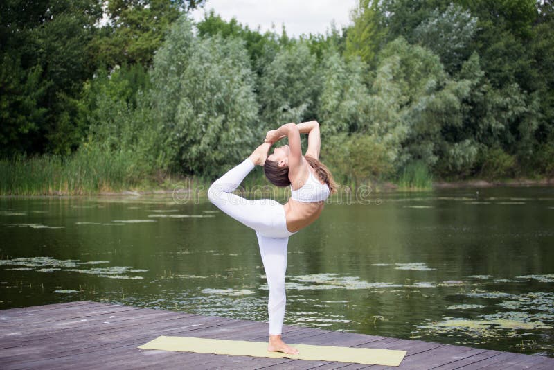 Unga flickan öva yoga på kusten av sjön, begreppet av att tycka om avskildhet och koncentration, solljus royaltyfri bild Unga flickan öva yoga på kusten av sjön, begreppet av att tycka om avskildhet och koncentration, solljus royaltyfri bild