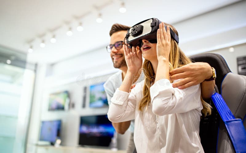 Unga, glada par som spelar videospel med virtuellt verklighetsglas i den tekniska butiken arkivbild