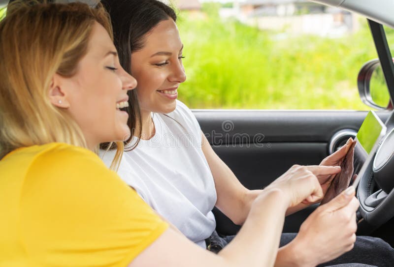 Unga kvinnor i bilen använder tabletten. arkivbild