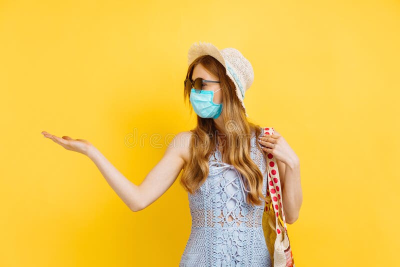Unga kvinnor i medicinska masker och sommarhatt på sommarplagg kan kopiera utrymme på gul bakgrund arkivfoto