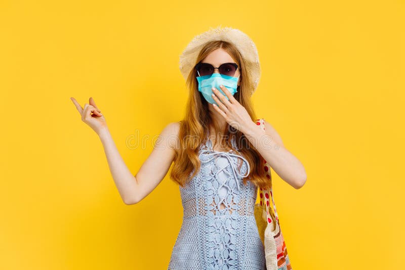 Unga kvinnor i medicinska masker och sommarhatt på sommarplagg kan kopiera utrymme på gul bakgrund royaltyfri fotografi