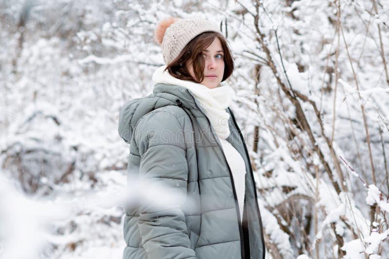 Unga kvinnor i vinterkläder bland träd täckta med snöflicka som går i snöskog och njuter av vackra naturområden arkivbilder