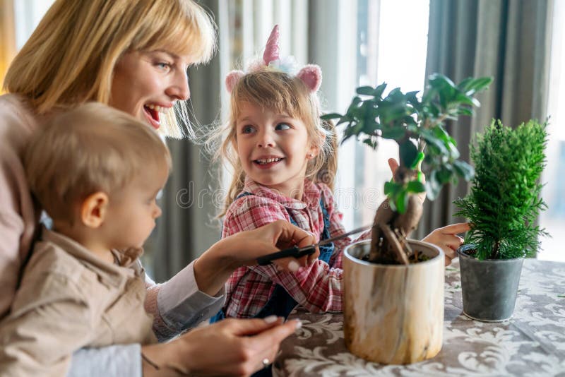 Unga kvinnor med barn som tar hand om växter inomhus. familjeträdgårdskoncept för trädgårdsmästare. royaltyfria foton