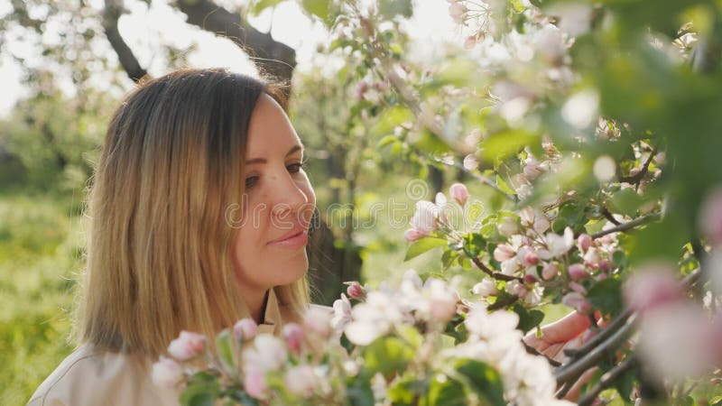 Unga kvinnor som beundrar blommande äppelträd i trädgården