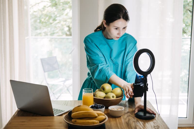 Unga kvinnor som filmar hälsosamt livsstilsinnehåll med frukt och juice i köket. välståndsbloggande och inflytande arkivbilder