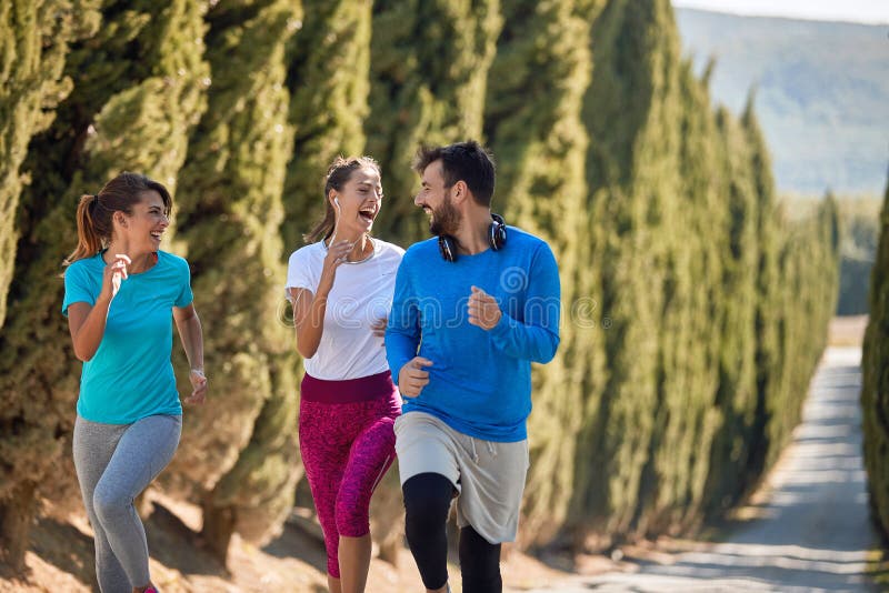 Unga kvinnor som har kul med sin personliga tränare medan de joggar royaltyfria bilder