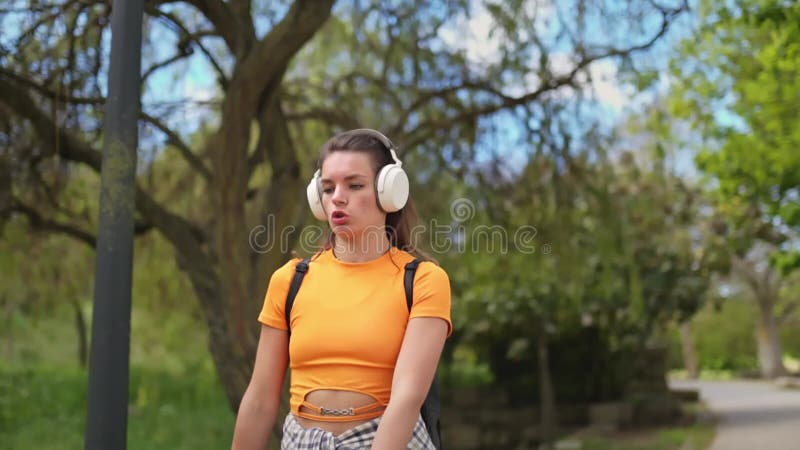 Unga kvinnor som lyssnar på musik när de går i parken arkivfilmer