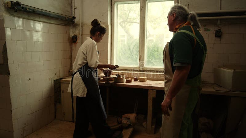 Unga kvinnor som producerar lerpott i lerskiffer. lärare som visar masterklass i studio arkivfilmer