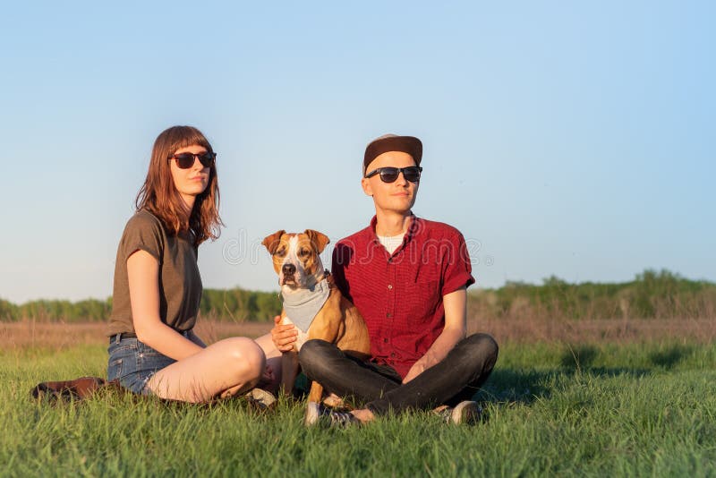 Unga lyckliga par av mannen och kvinnan med staffordshire terrier D arkivfoto Unga lyckliga par av mannen och kvinnan med staffordshire terrier D arkivfoto