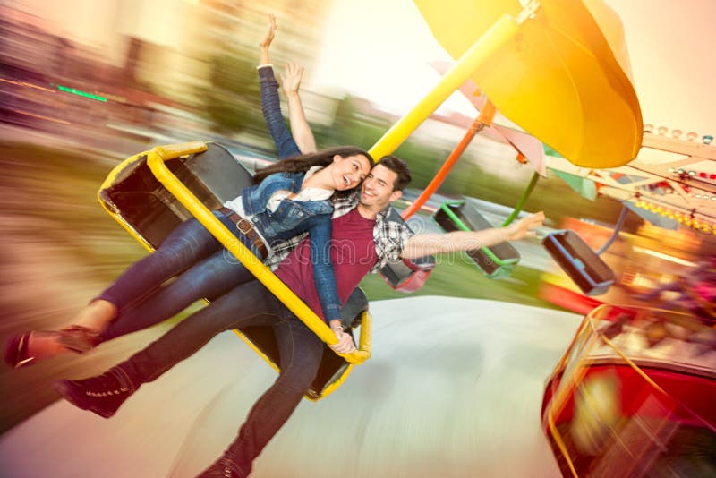 Young happy couple having fun at amusement park, riding on carousel. Young happy couple having fun at amusement park, riding on carousel